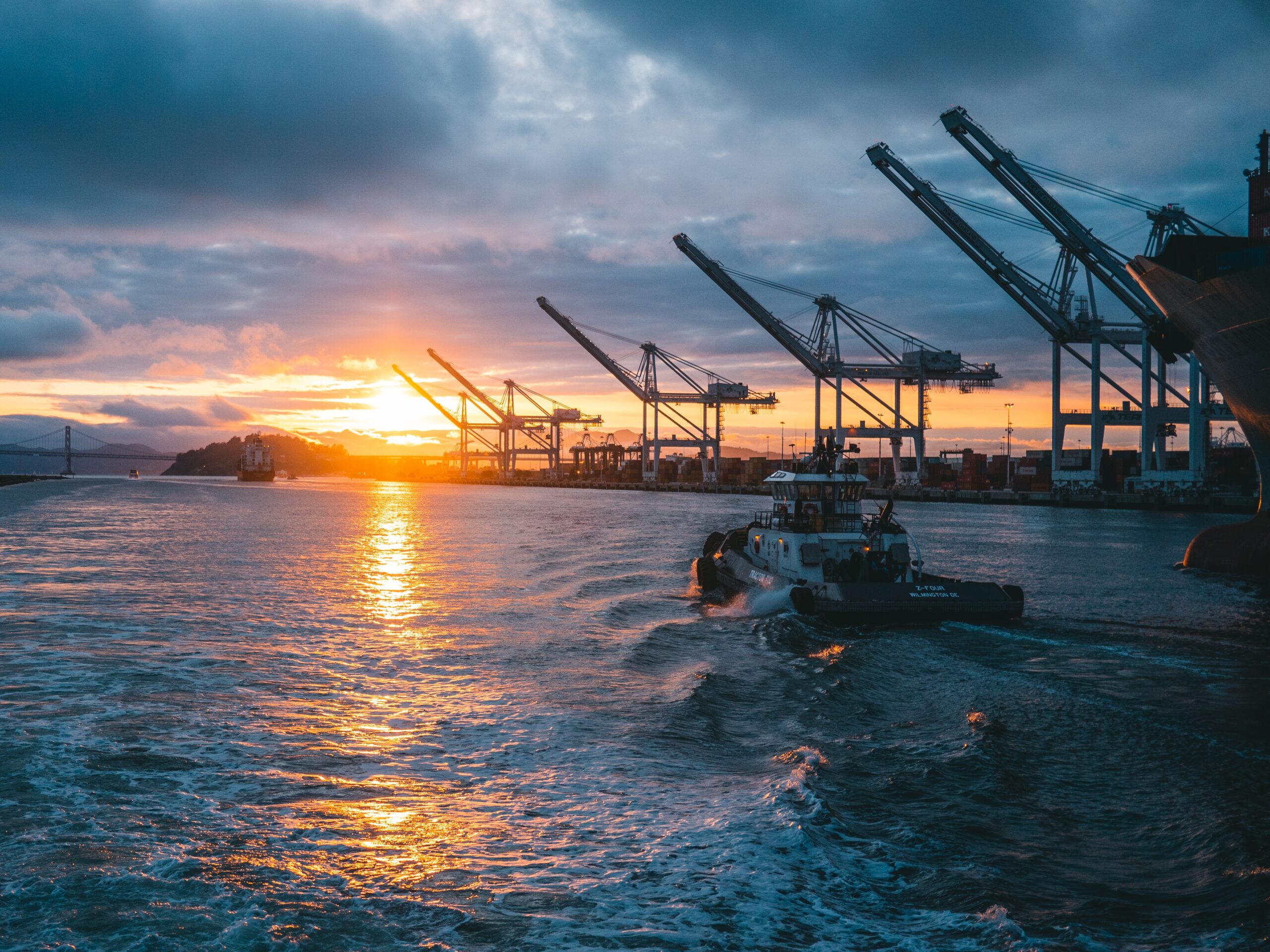 a panoramic shot of oil rigs at sea with a beautiful sunset in the background, under cloudy sky